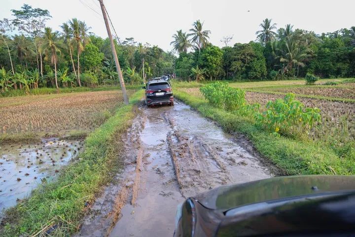 Foto: Mobil rombongan melintasi jalan rusak dan berlumpur di Kampung Grewel, Desa Karya Jaya, Kecamatan Cimarga, Kabupaten Lebak, Rabu (27/8/2025).