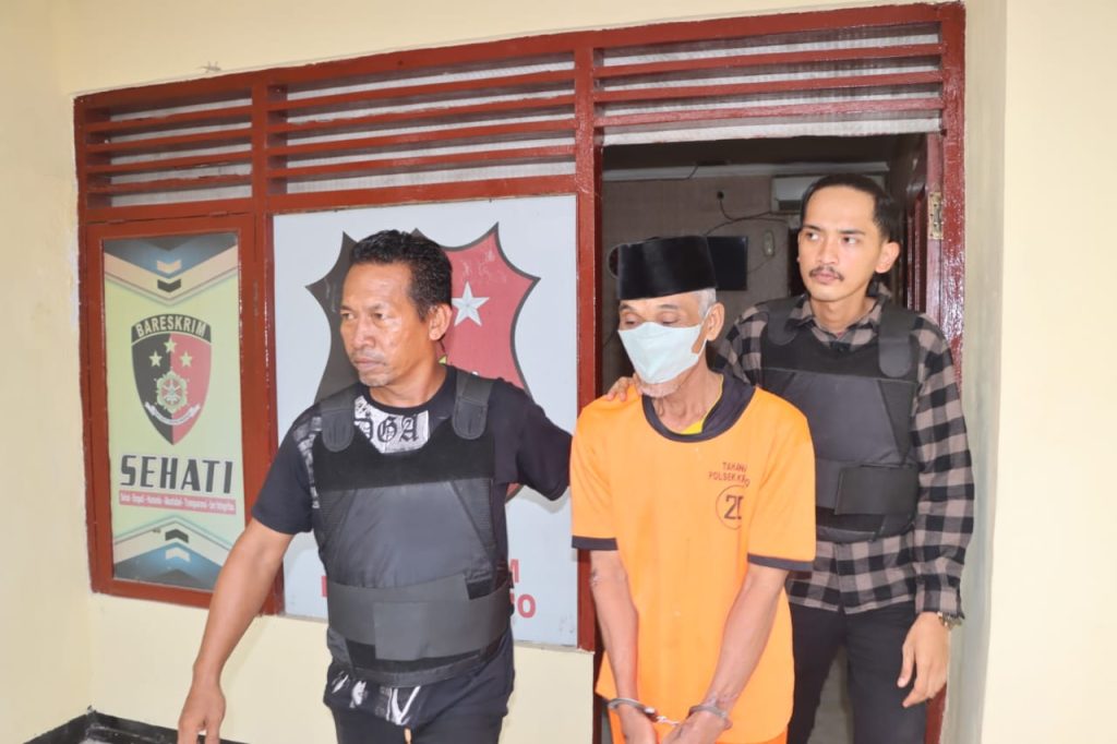 Keterangan Foto: Tersangka S (66) saat digiring anggota Unit Reskrim Polsek Kronjo usai diamankan terkait kasus penyiraman cairan kimia ke pasangan suami istri tetangganya, Senin (15/9/2025).